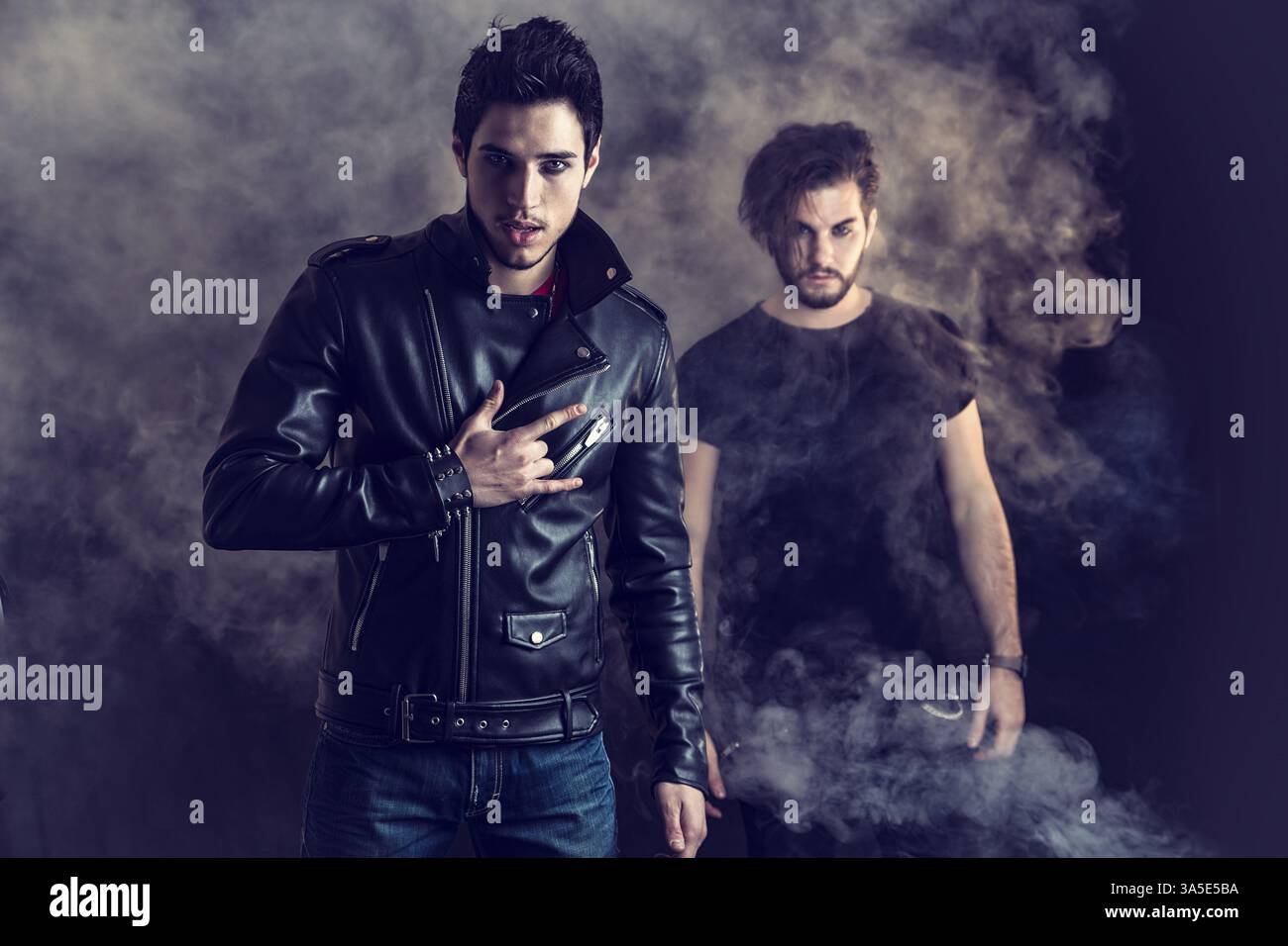 Two attractive young hard rock men posing in studio. Black background Stock Photo
