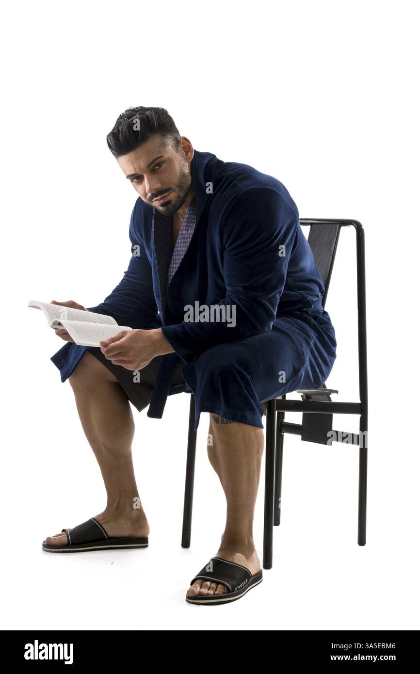 Handsome muscular male in bathrobe or nightrobe holding a book, isolated on white background Stock Photo