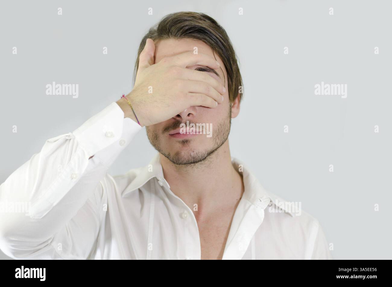 Attractive young man covering eyes with his hand Stock Photo - Alamy