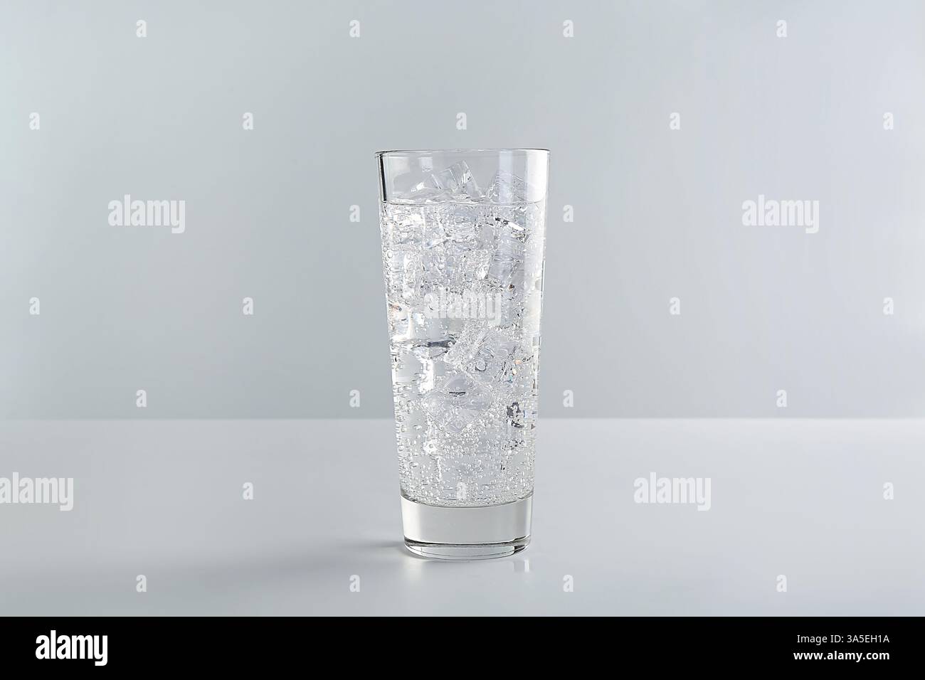 Refreshing soda water with ice cubes in glass on white table against ...