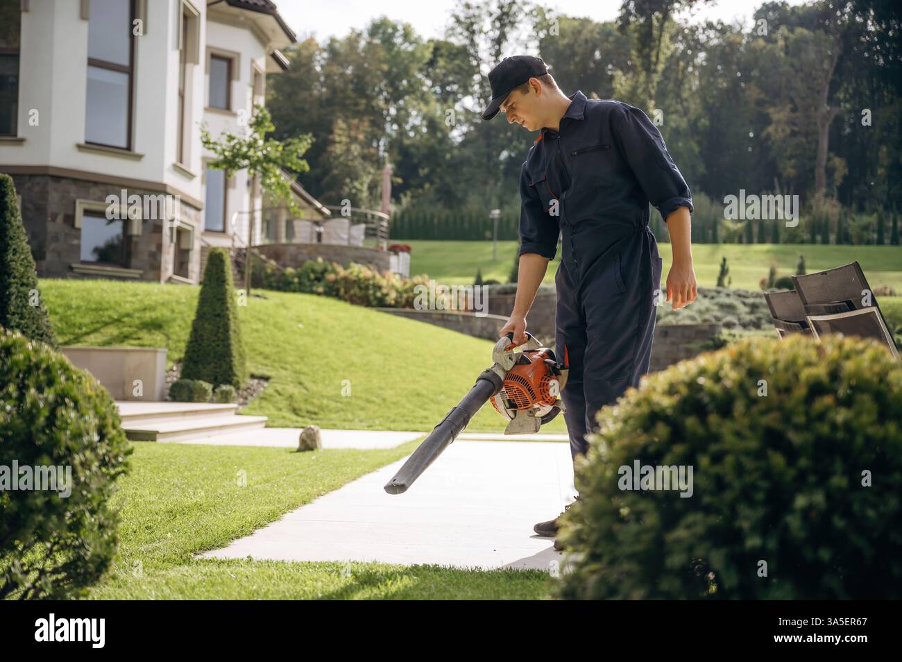 Using leaf blower. Professional gardener is on the lawn. Stock Photo