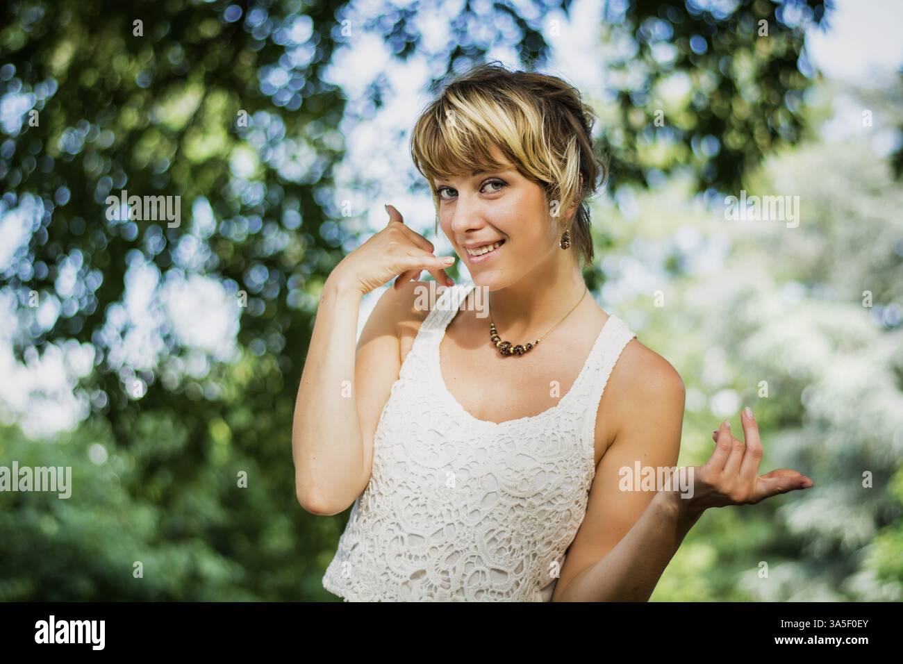 Pretty blonde young woman doing call me sign with hand as a symbol of ...