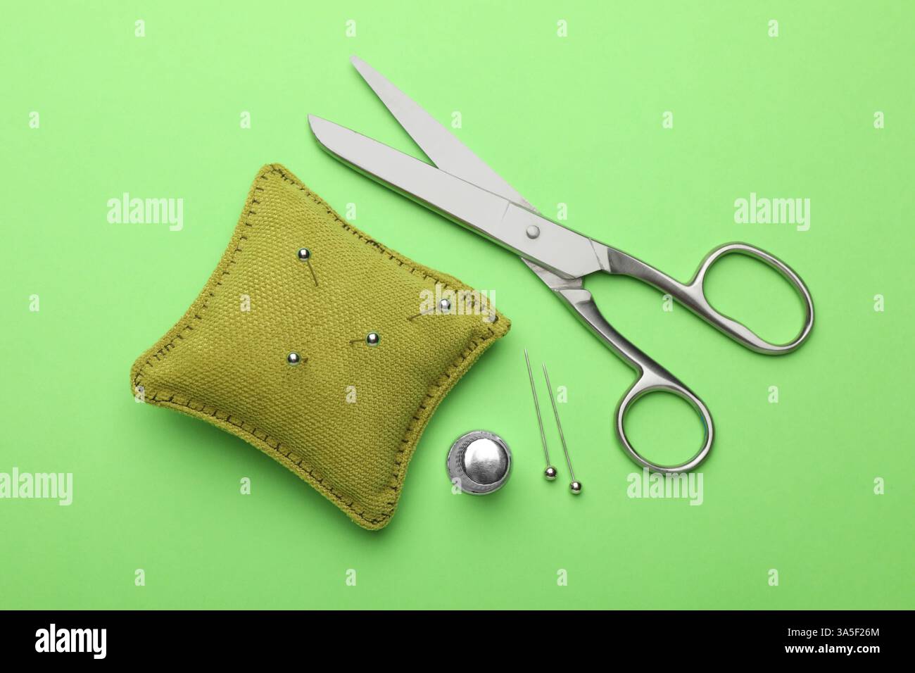 Different sewing supplies on green background, flat lay Stock Photo