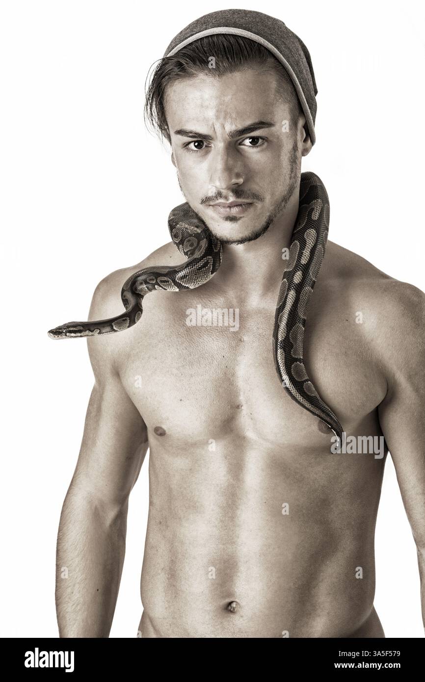 Three Quarter Length Portrait of Muscular Man with Shaved Head Standing in Studio with White Background, with Small Python Snake Wrapped Around Neck Stock Photo