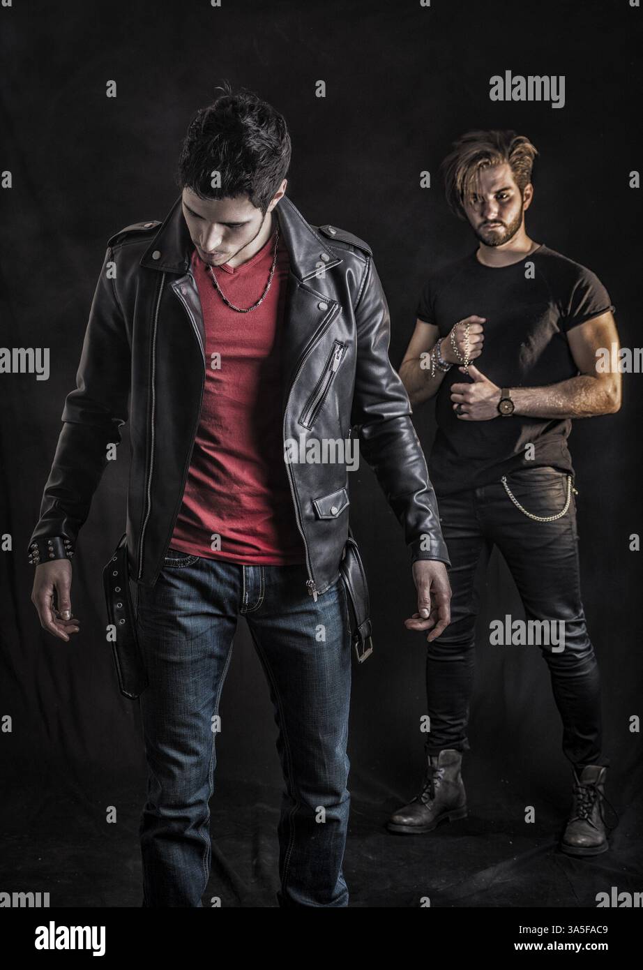 Two attractive young hard rock men posing in studio. Black background Stock Photo