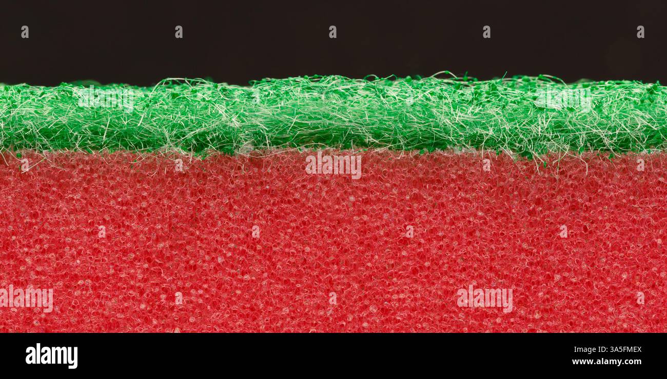 Two-color, two-layer dishwashing sponge close-up on a dark background. Macro photography. Stock Photo