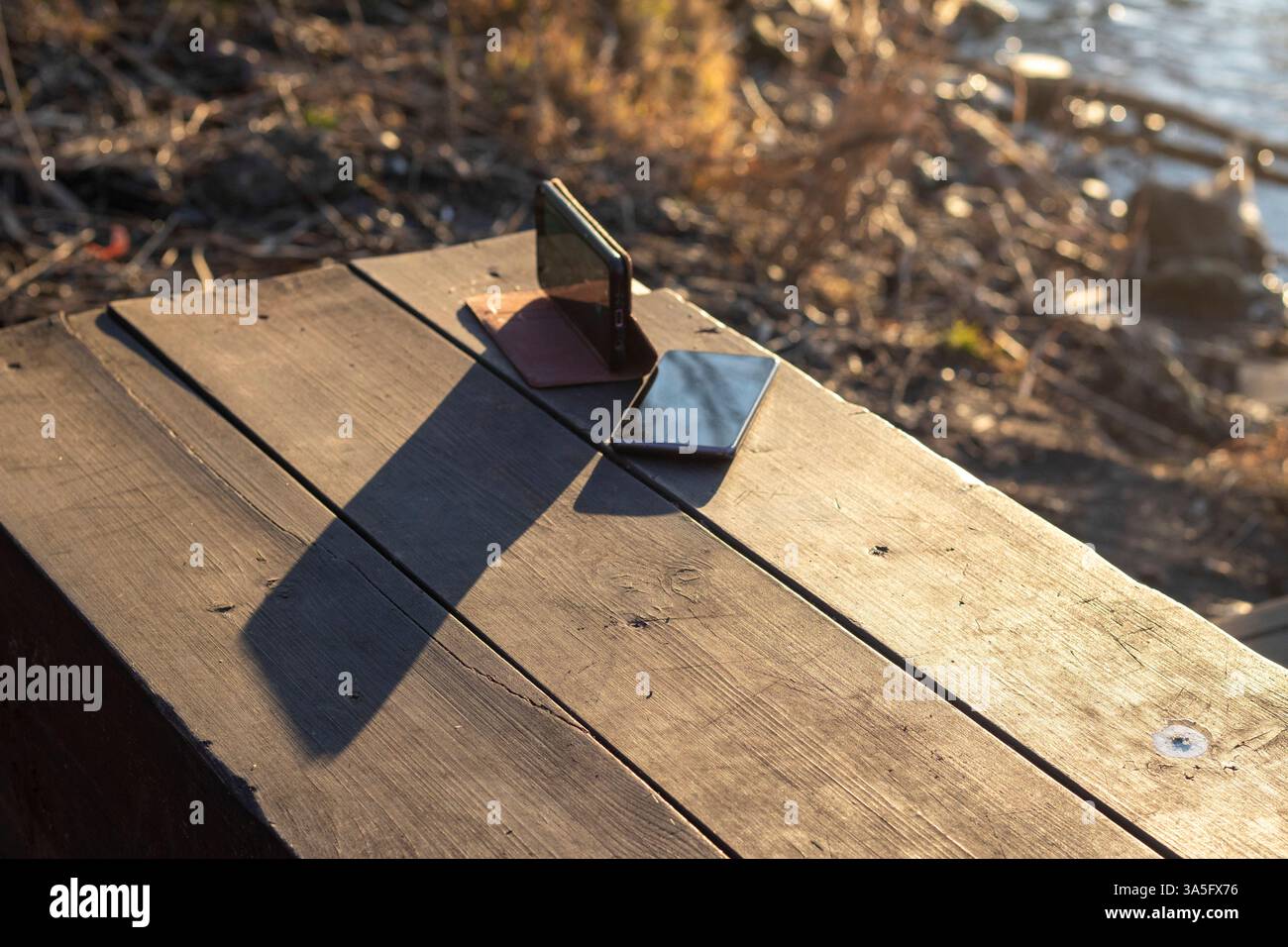 Shot of the two mobile phones on the wooden bench Stock Photo