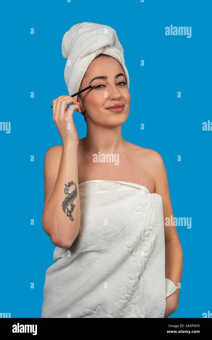 Young woman wearing a towel applying mascara after a shower Stock Photo