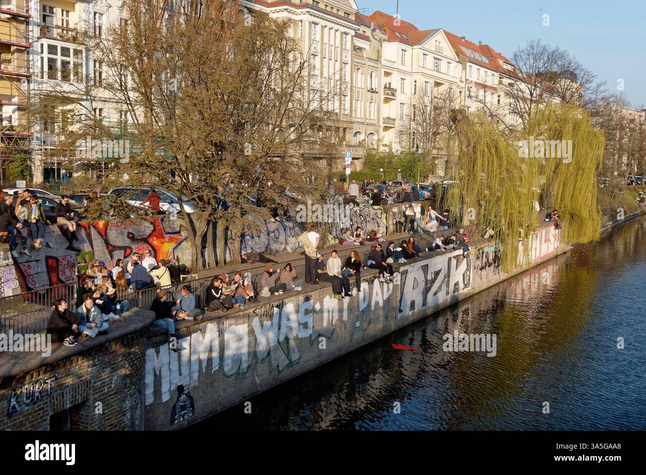 Junge Leute sitzen in Gruppen am Landwehrkanal in Kreuzberg, Berlin