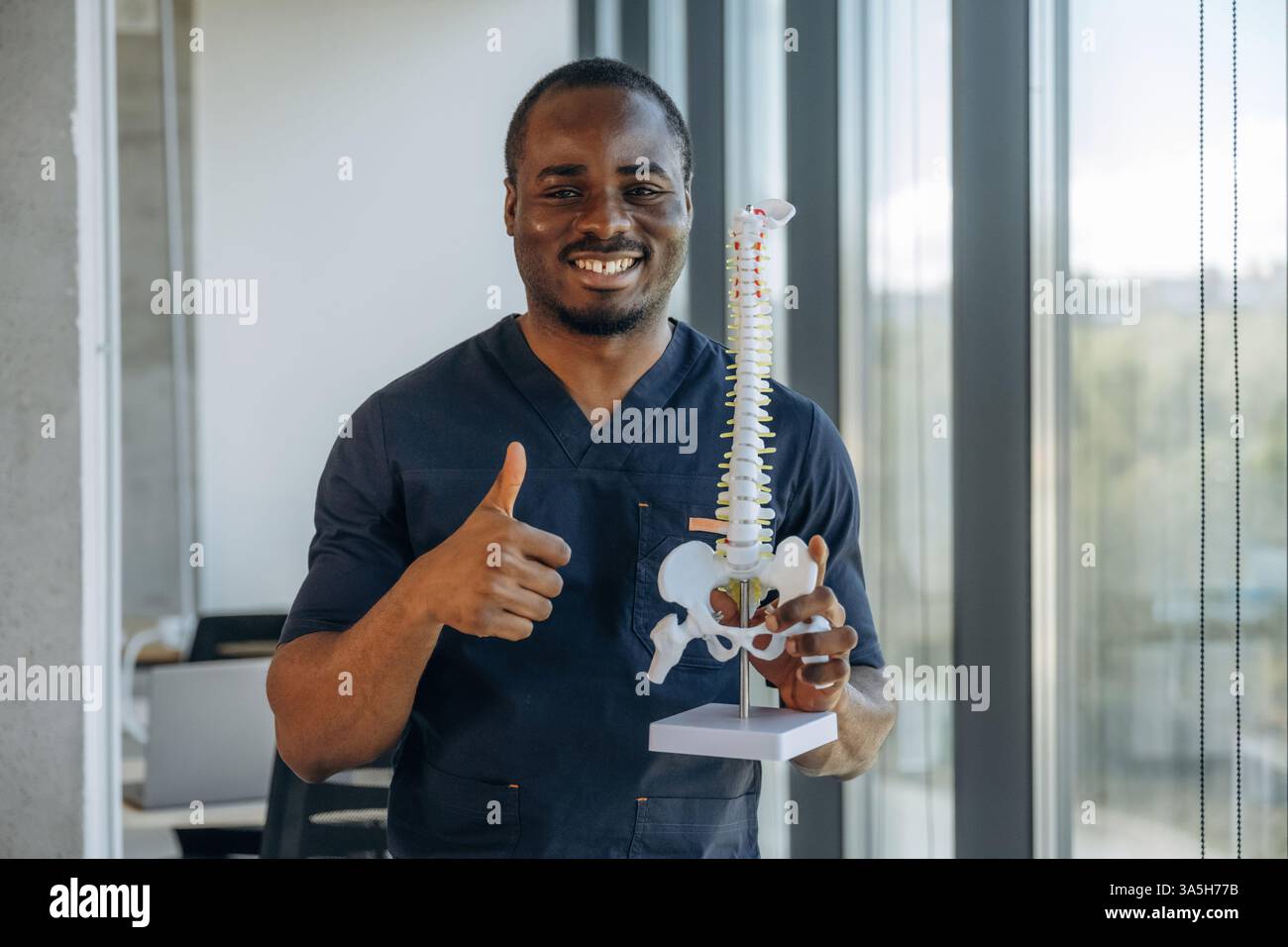 Thumb up, holding spine model. Professional doctor is in his office ...
