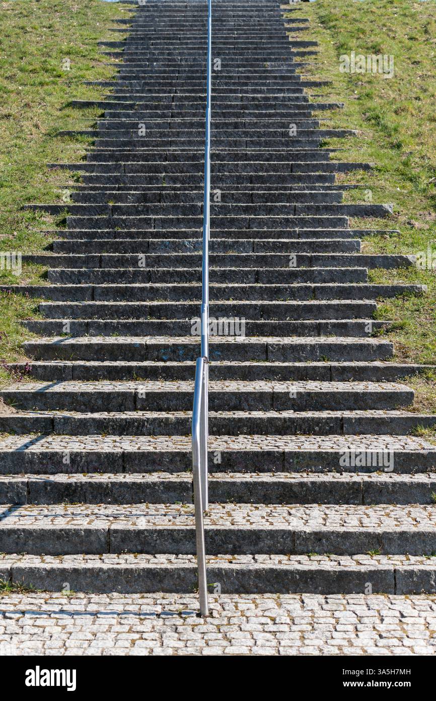 A metal railing is on the side of a staircase. The railing is silver ...