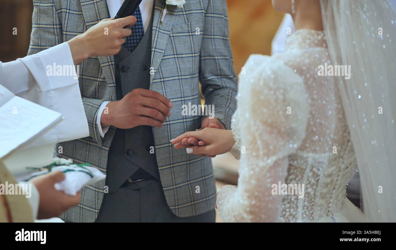 Priest Rings Bride and groom exchanging wedding rings during a heartfelt ceremony ...