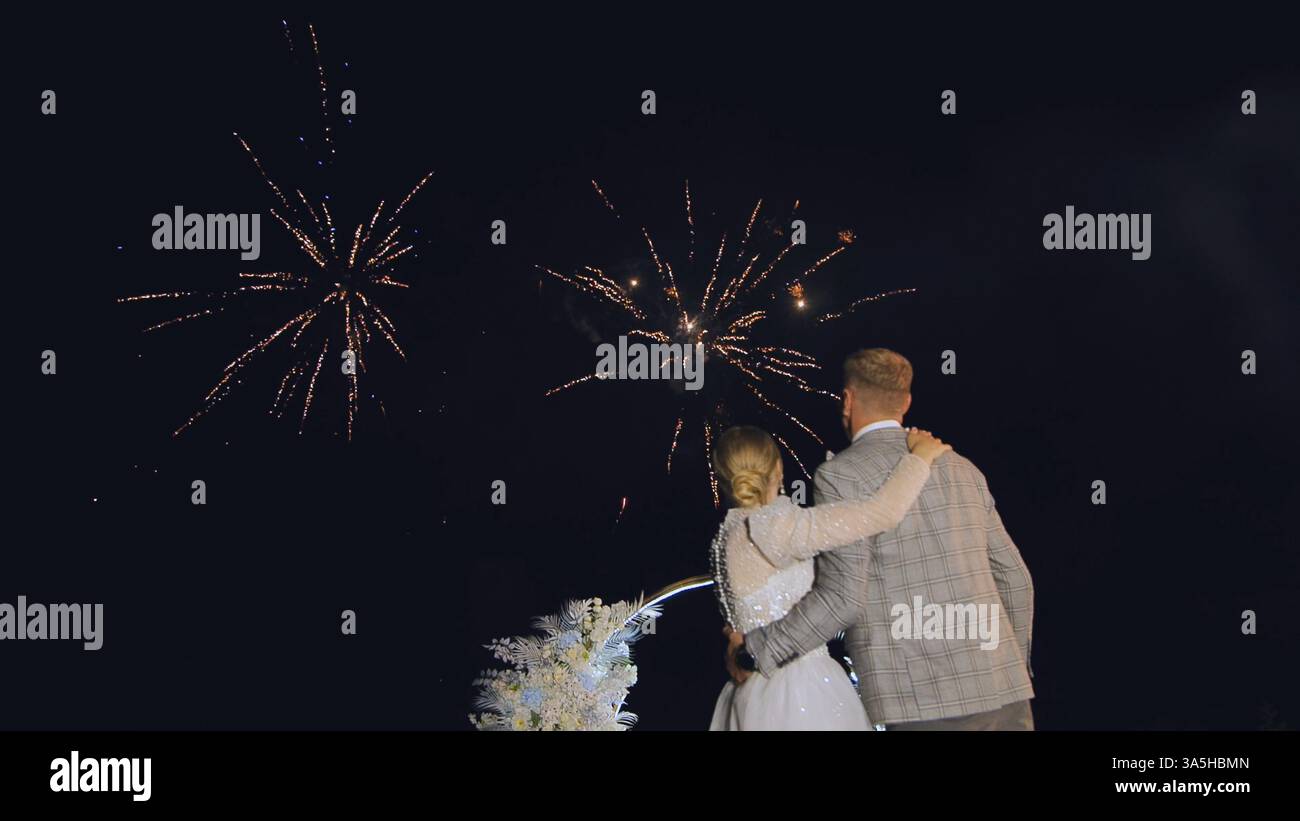 Intimation Night Newlywed couple kissing beneath dazzling fireworks, sharing intimate ...