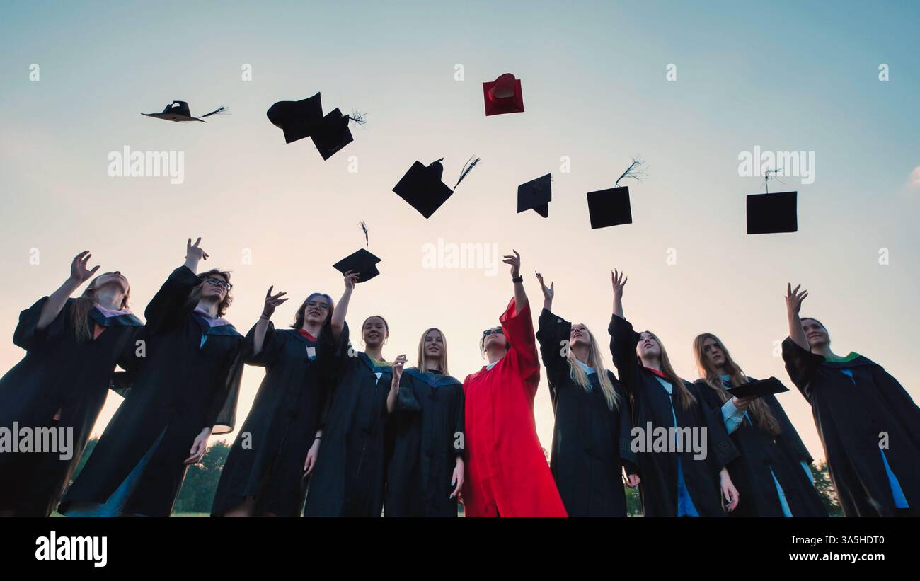 Graduating students joyfully throwing their caps into the air against a ...