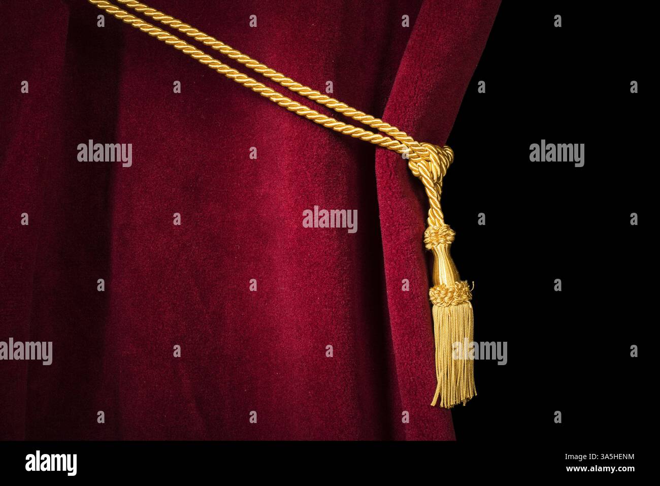 Red velvet curtain with tassel. Close up black isolated curtain Stock Photo