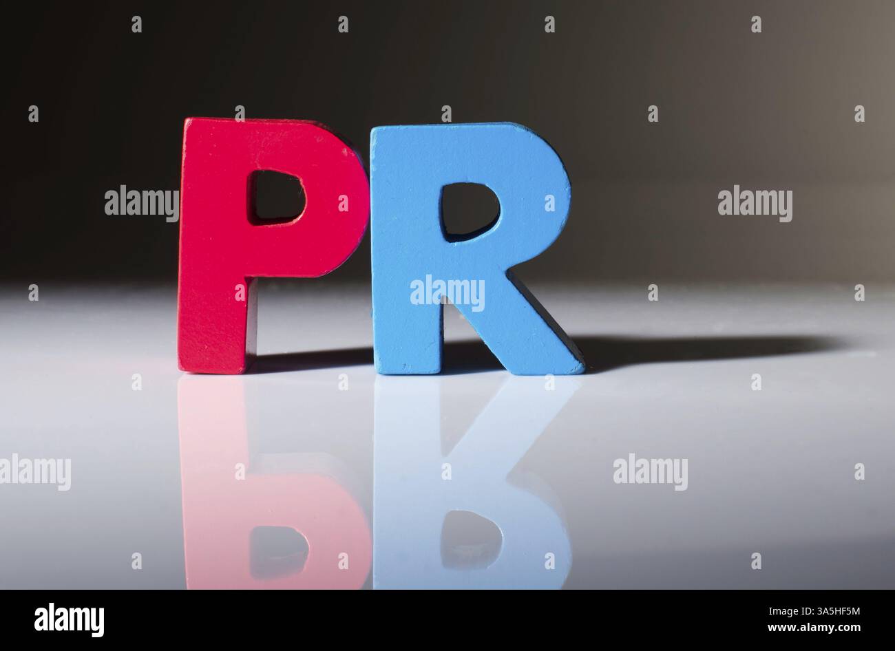 Multicolored text PR made of wood. White background Stock Photo