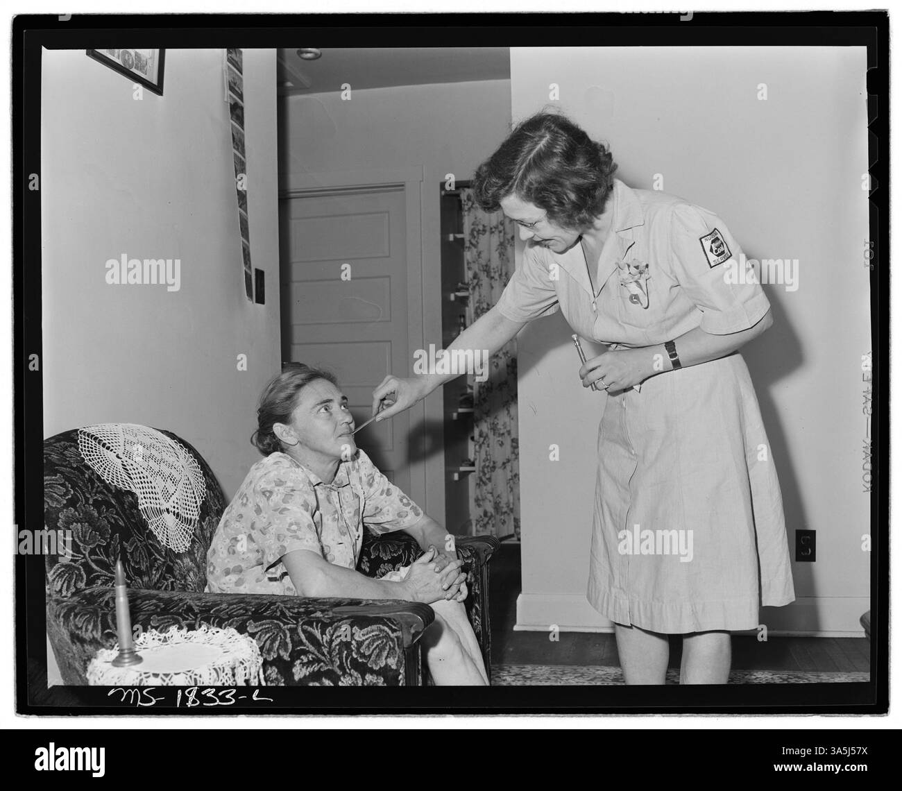 Miss Hazel Jamison, a registered nurse, visits Mrs. Charles Gross, the wife of a miner at the Koppers Coal Division in Kopperston, Wyoming County, West Virginia, to monitor her recovery while staying in company housing. The photograph documents a healthcare visit within a mining community. Stock Photo