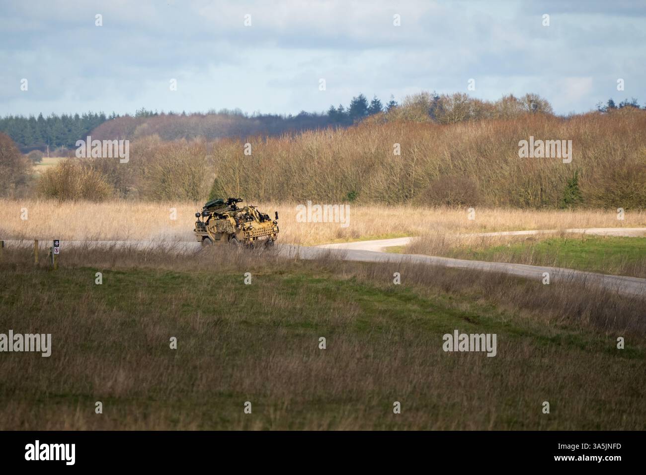 beige support and recon vehicle moving along a dirt track Stock Photo