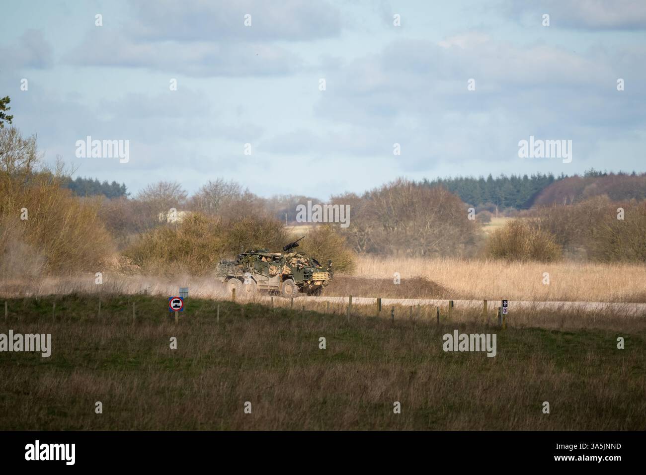 beige support and recon vehicle moving along a dirt track Stock Photo