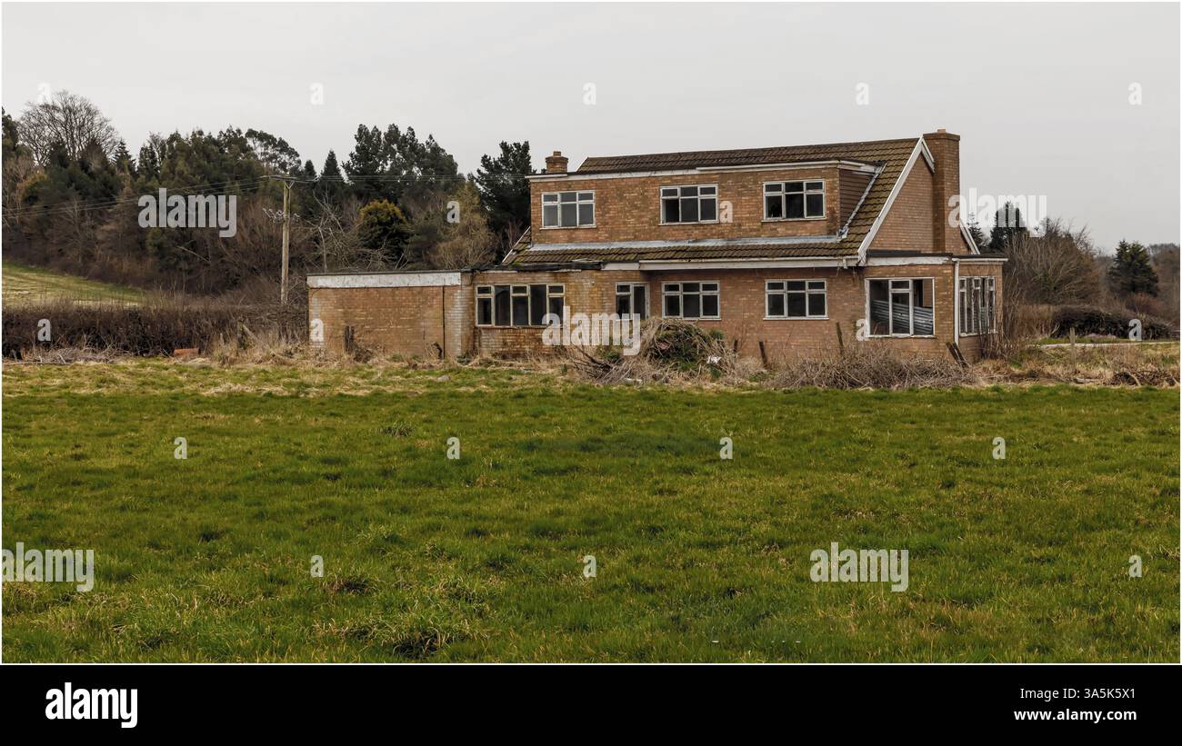 Kelsall, Cheshire, UK - February 21st 2025 - Back view of a derelict house in a field with smashed windows Stock Photo