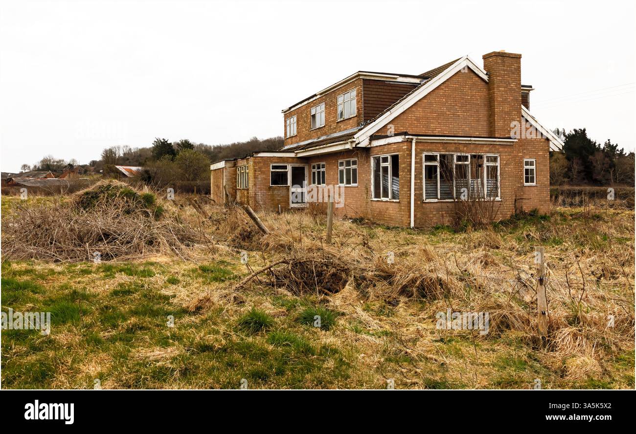 Kelsall, Cheshire, UK - February 21st 2025 - Corner view of a derelict house in an overgrown field Stock Photo