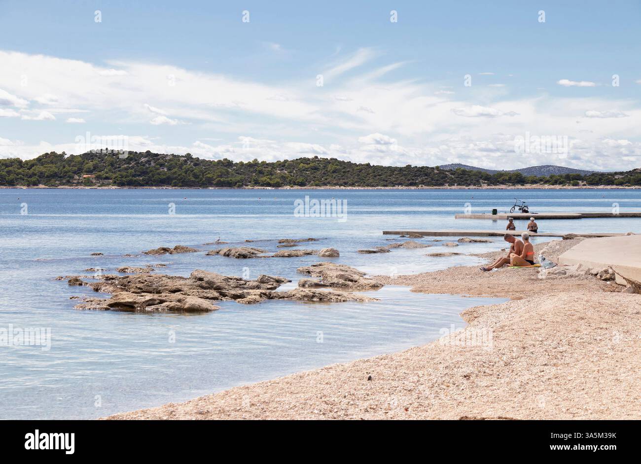 Vodice, Croatia - September 14 2024: Pebble beach in off season with few people relaxing Stock Photo