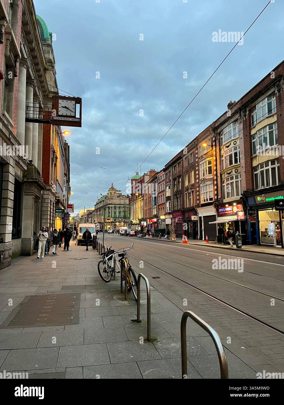 A lively street in Dublin, Ireland, at dusk, with historic buildings lining the tram tracks. - Smartphone Captured Stock Image