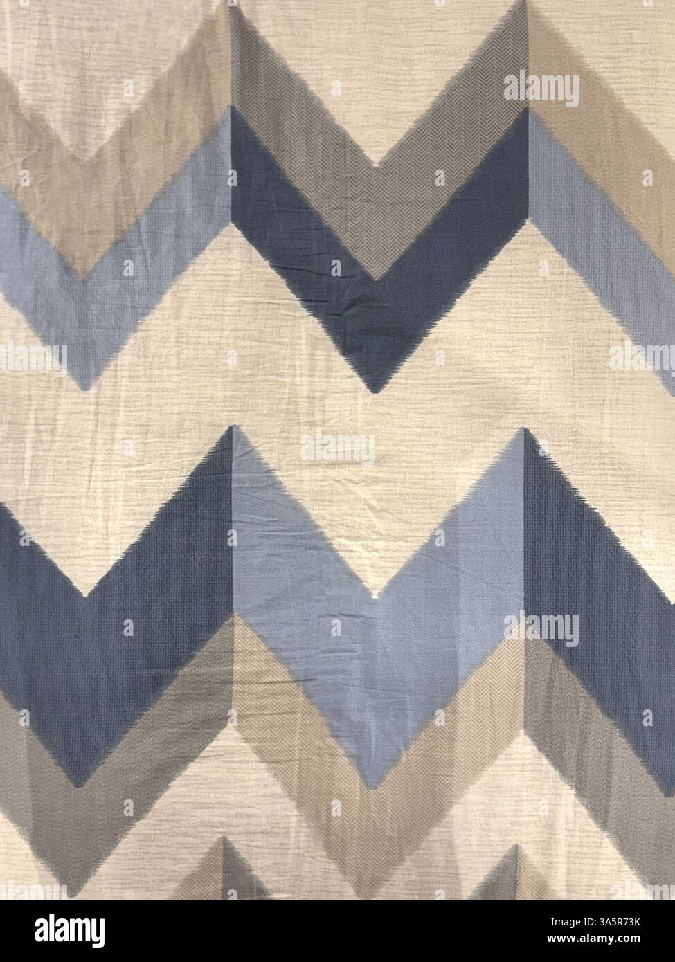 Close up of nylon fabric with arrow chevron V shape pattern in shades of blue, grey, and pale brown color. Fabric seamless background texture. Stock Photo