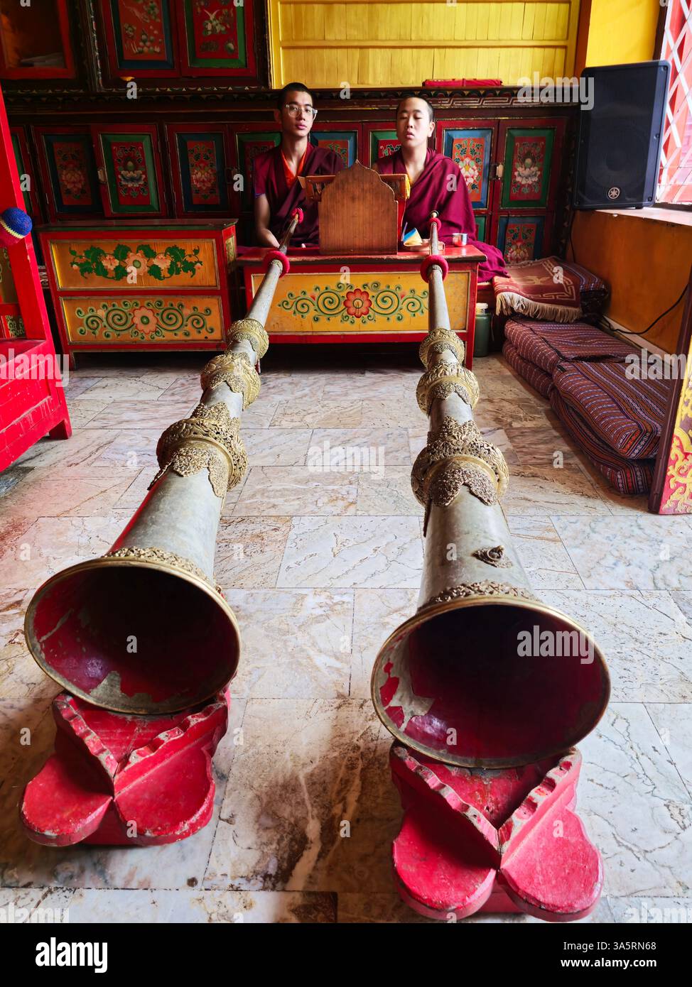 Tibetan monks sounding their traditional horns during a religious ceremony in a small monastery in the Boudhanath area in Kathmandu, Nepal. - Smartphone Captured Stock Image