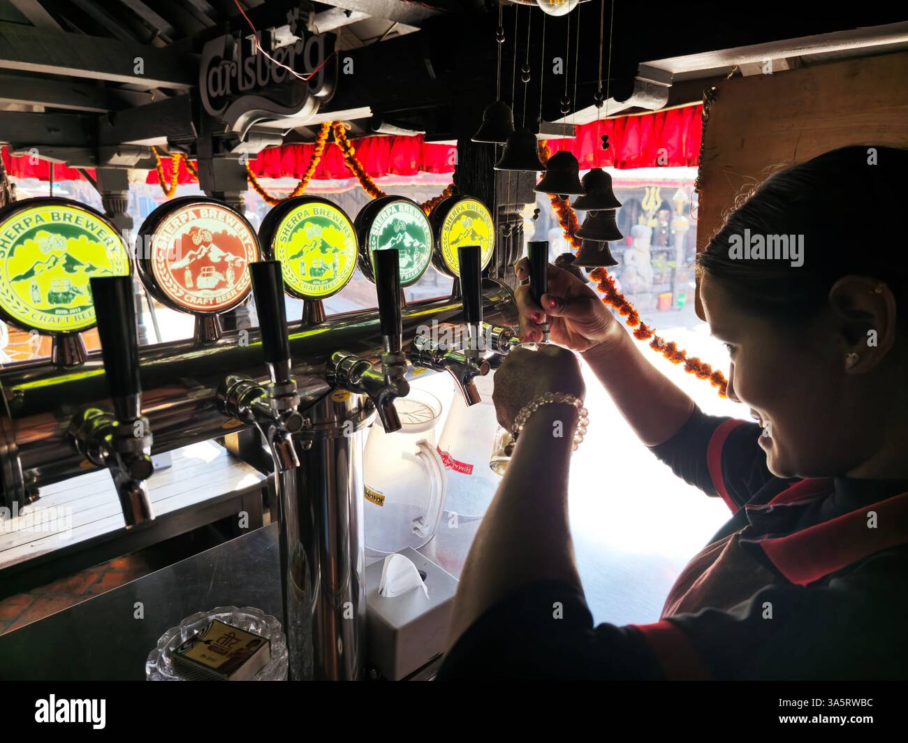 A bartender pouring craft Sherpa draft beer in a local pub restaurant in Bhaktapur, Nepal. - Smartphone Captured Stock Image