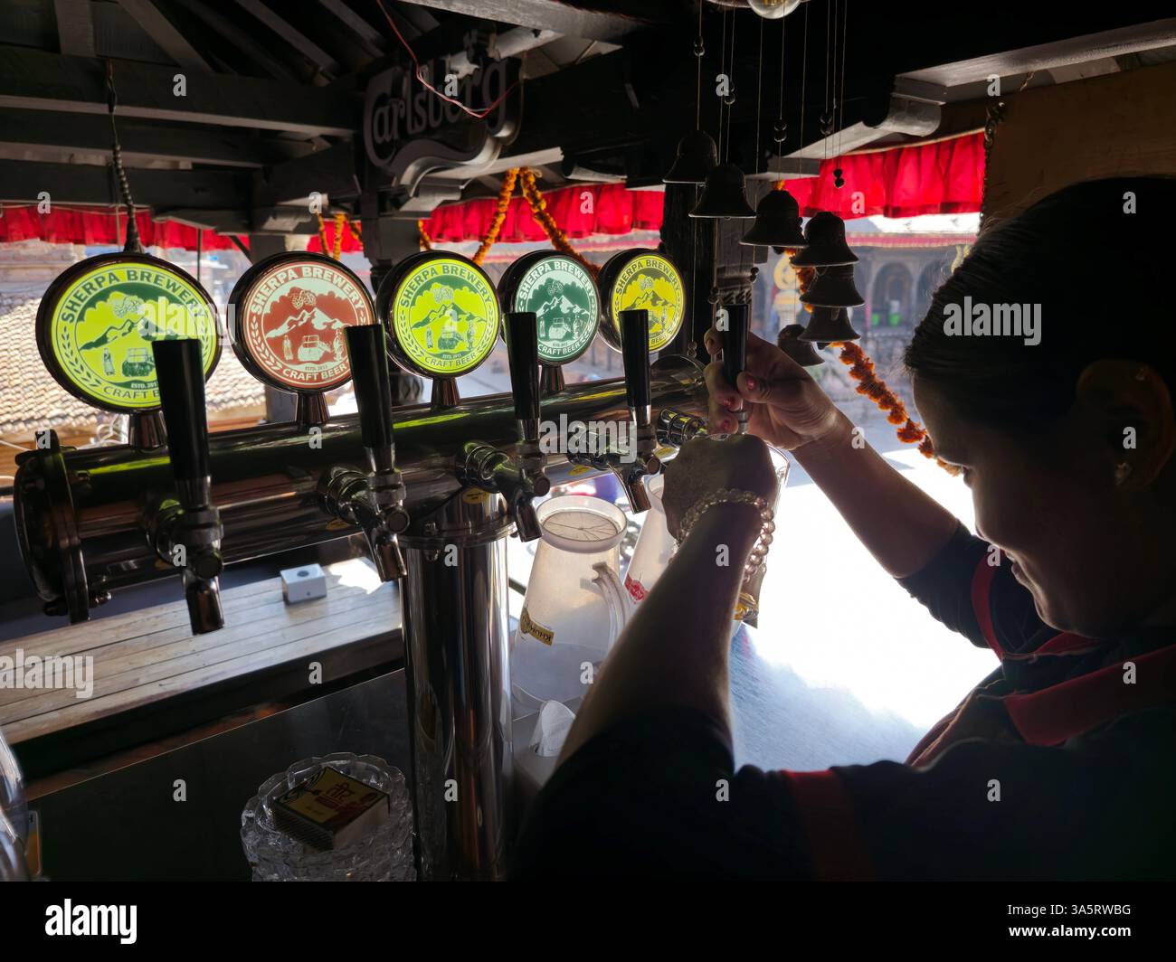 A bartender pouring craft Sherpa draft beer in a local pub restaurant in Bhaktapur, Nepal. - Smartphone Captured Stock Image
