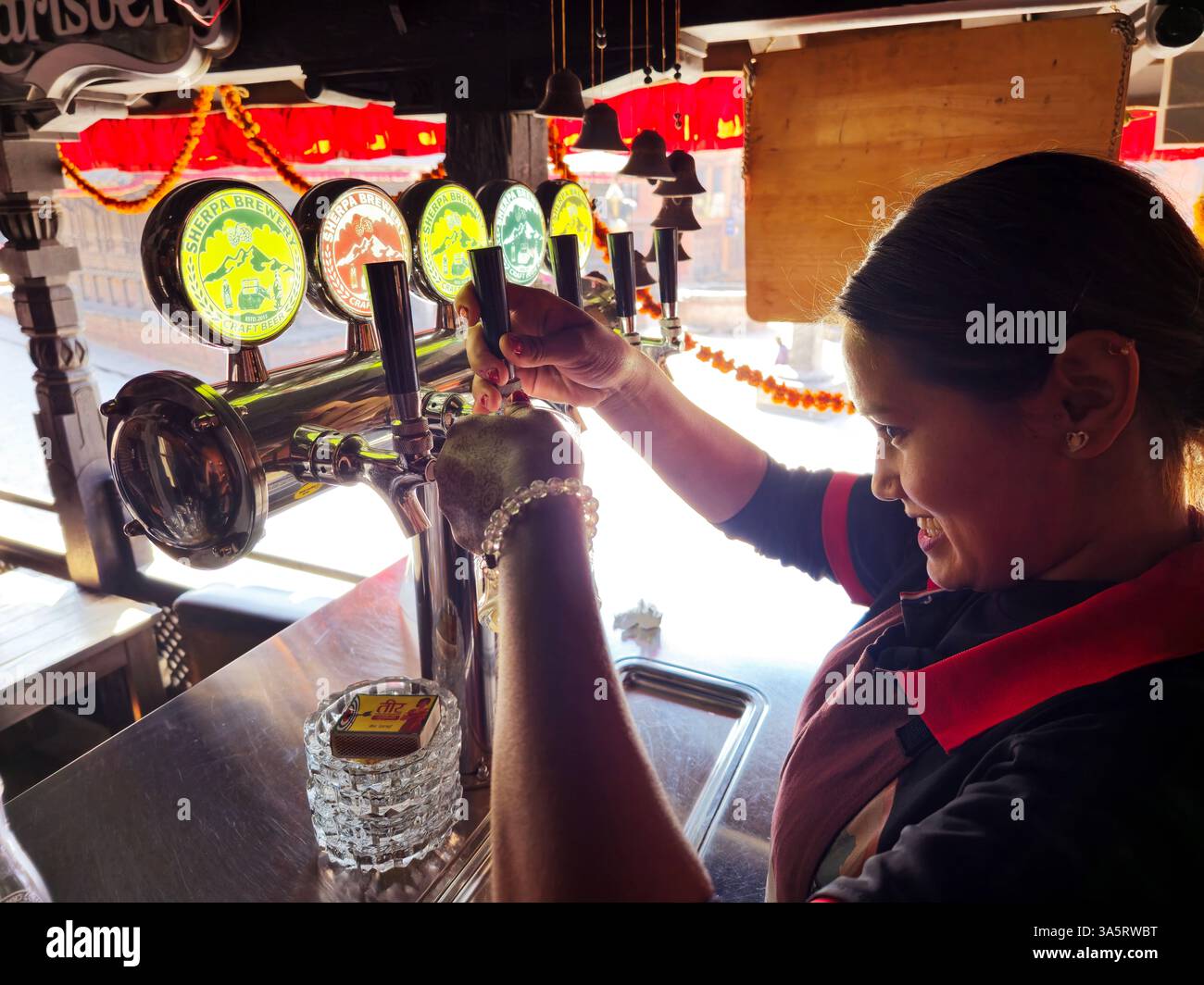 A bartender pouring craft Sherpa draft beer in a local pub restaurant in Bhaktapur, Nepal. - Smartphone Captured Stock Image