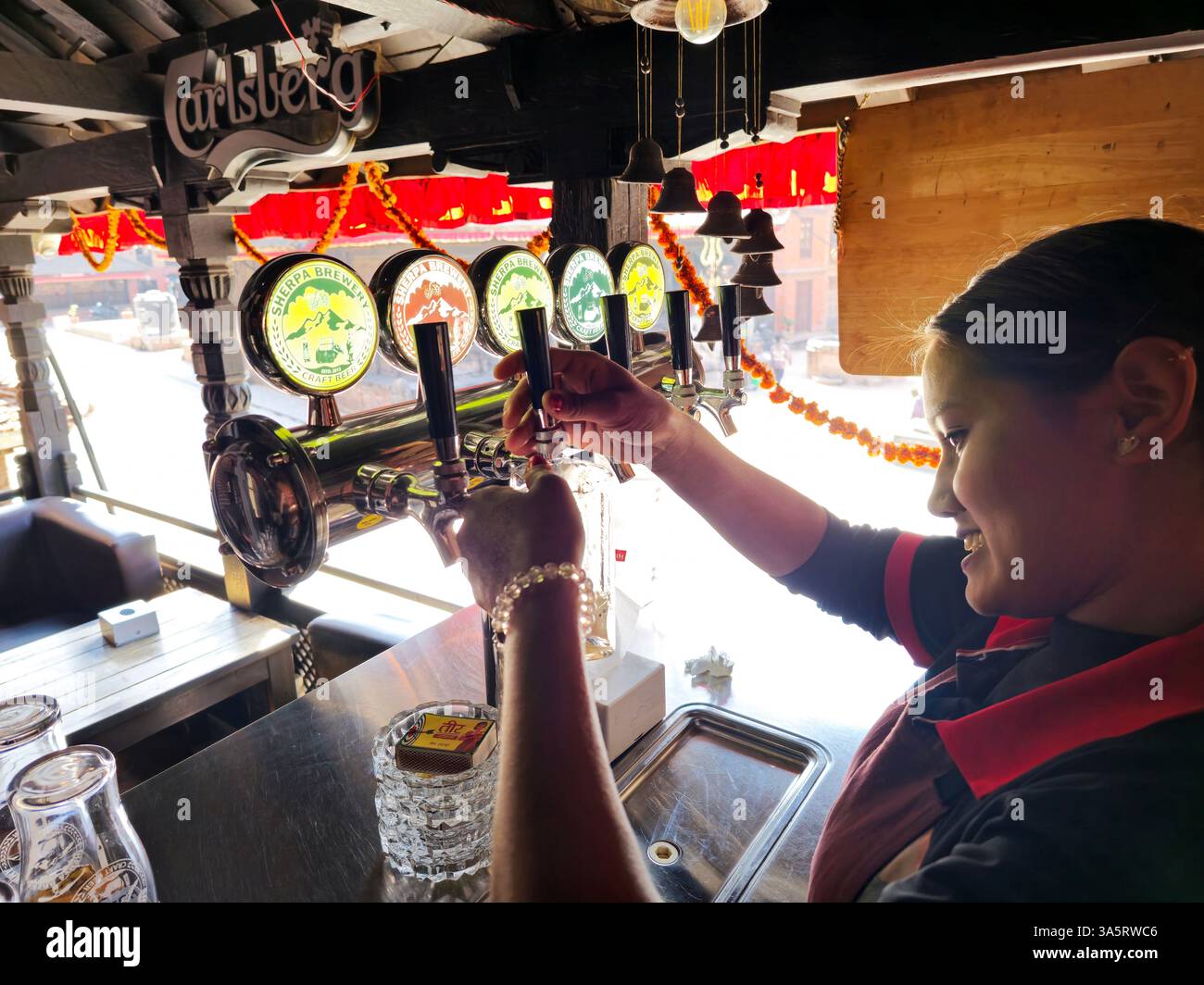 A bartender pouring craft Sherpa draft beer in a local pub restaurant in Bhaktapur, Nepal. - Smartphone Captured Stock Image