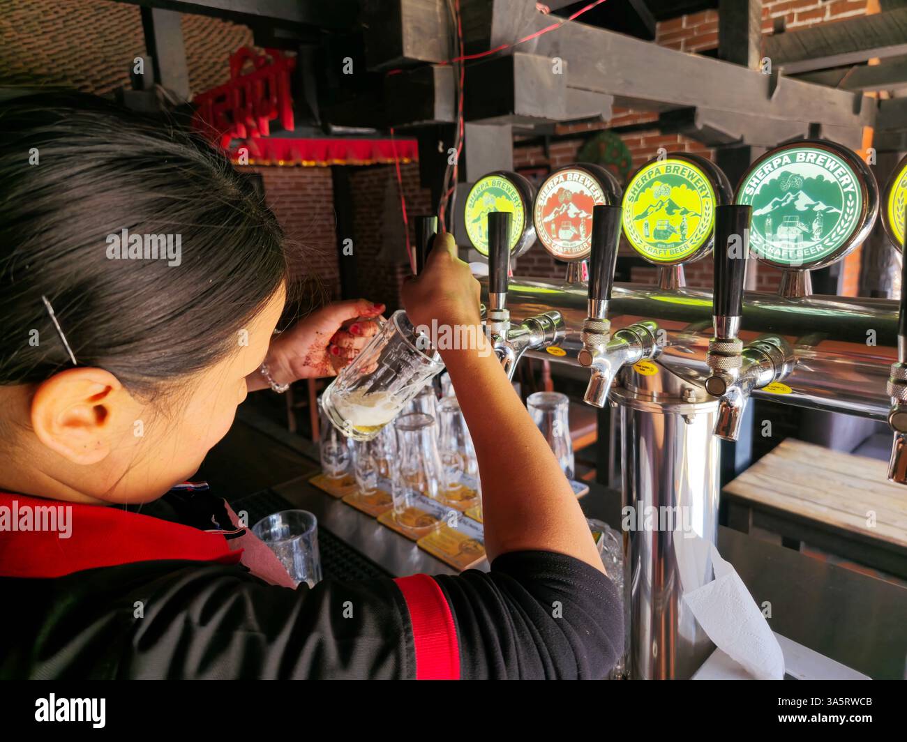 A bartender pouring craft Sherpa draft beer in a local pub restaurant in Bhaktapur, Nepal. - Smartphone Captured Stock Image