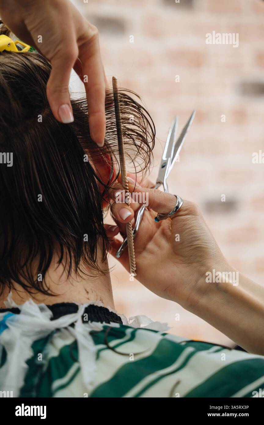 A professional barber using scissors and a comb to cut a client's hair, showcasing precision Stock Photo