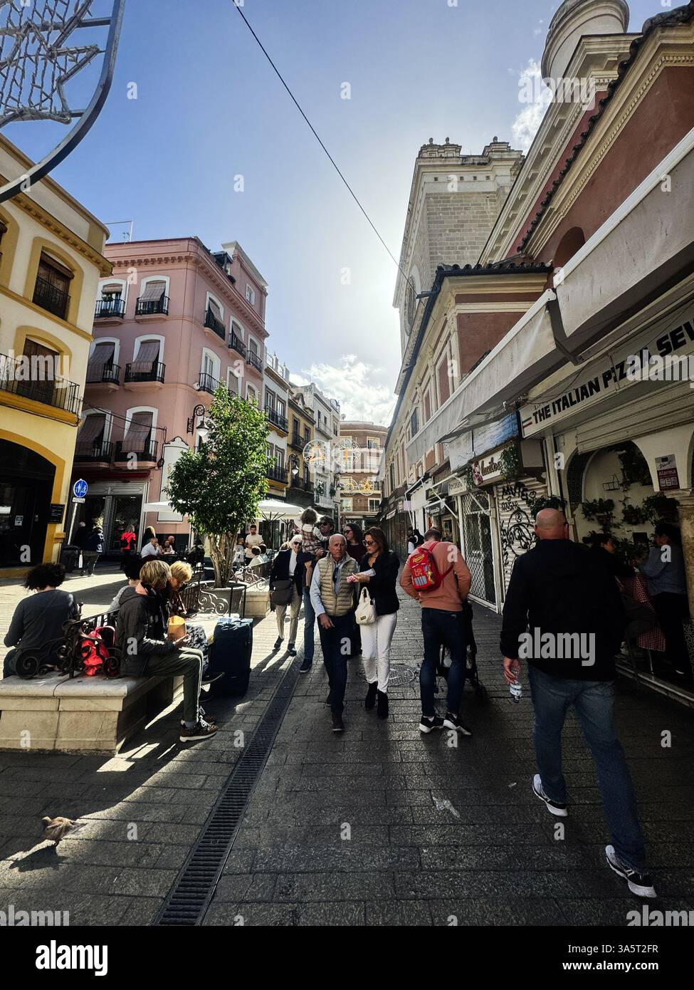 Seville, Spain - November 05, 2023: Pedestrians enjoying a bright day in a historic European city's charming street in Seville, Spain. Stock Photo