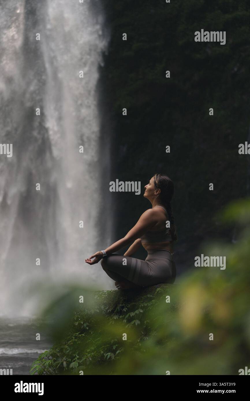 Woman practising yoga in front of waterfall on the island of Bali Stock ...