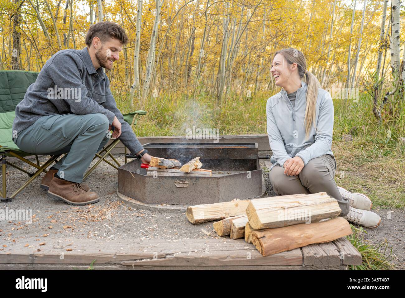 Couple Builds Fire While Camping Stock Photo Alamy