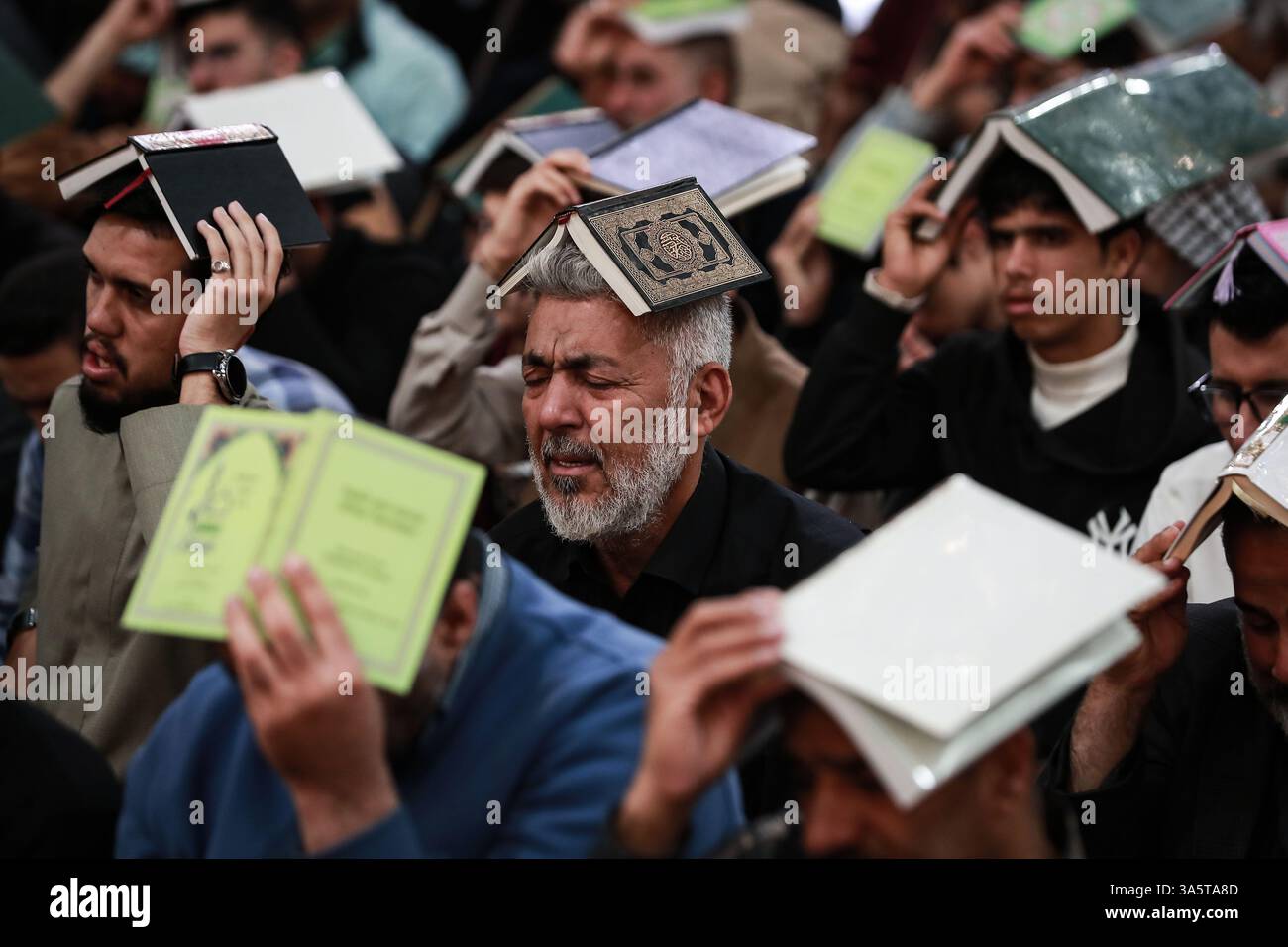 Karbala, Iraq. 23rd Mar, 2025. Iraqi Shiite Muslims hold copies of the ...