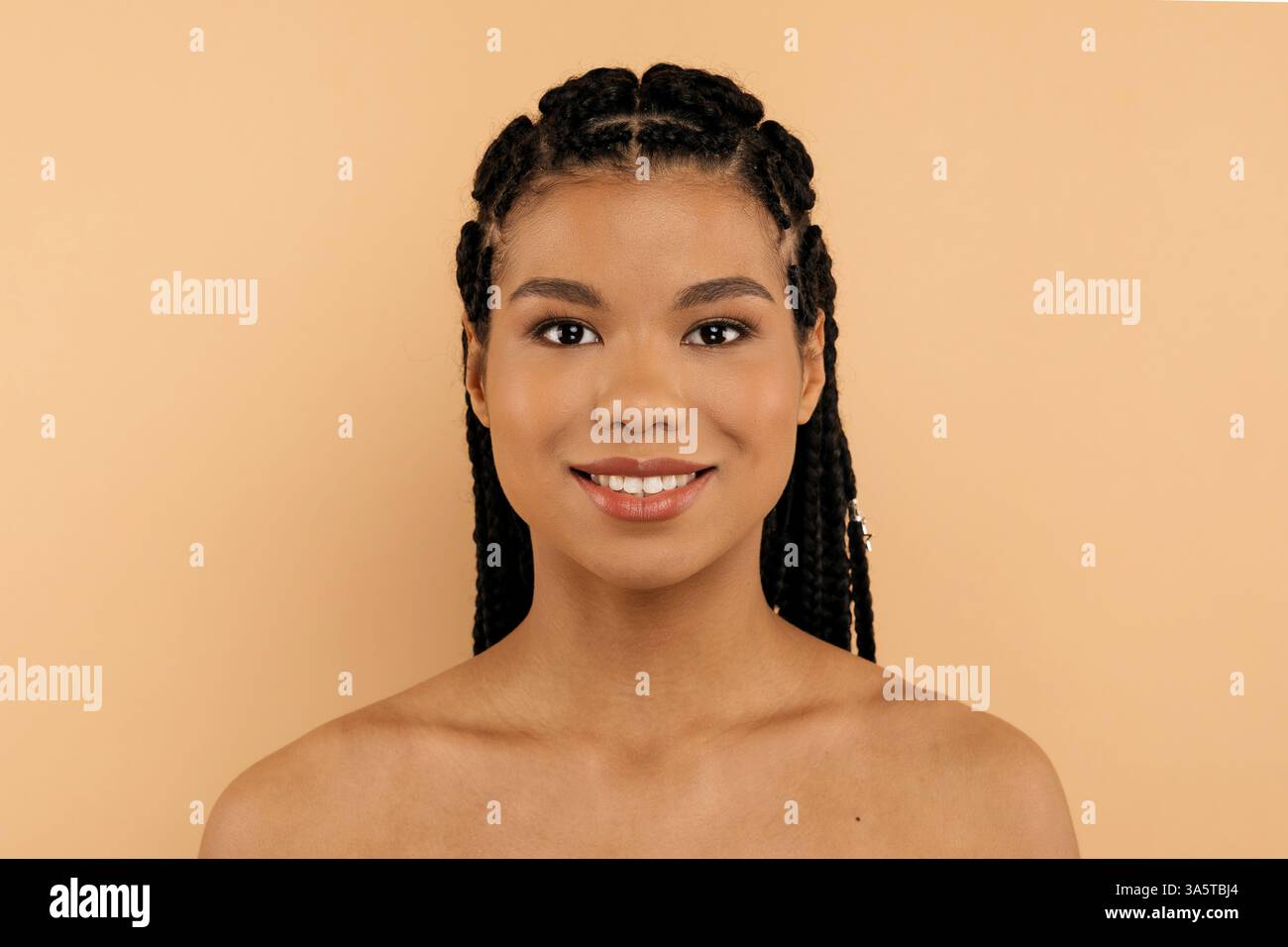 Portrait of beautiful African American woman with braids on beige ...