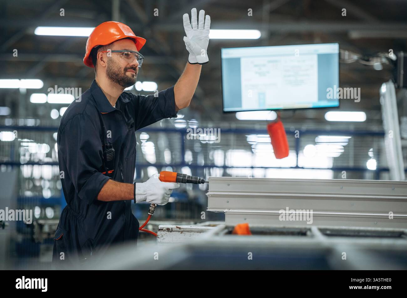 Using screwdriver. Man is working in the modern factory. Stock Photo