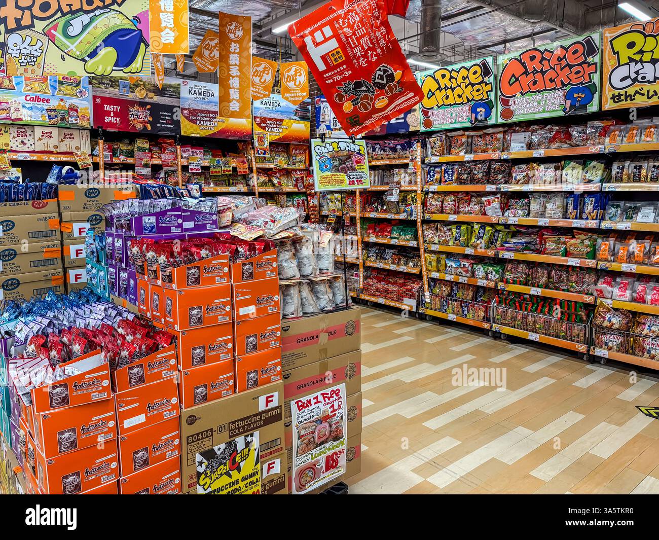Don Don Donki discounted store aisle in Japan with piles of rice crackers and japanese candy on display and for sale. Stock Photo