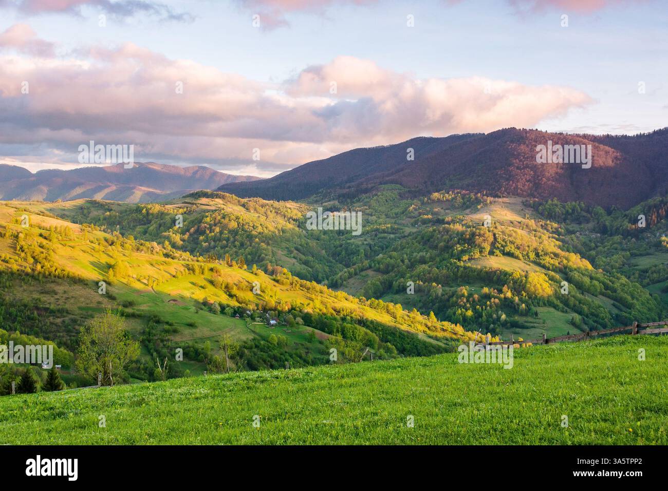 mountain landscape in spring. scenic view of rural valley. countryside scenery with rolling hills. sky with clouds in evening light. natural environme Stock Photo