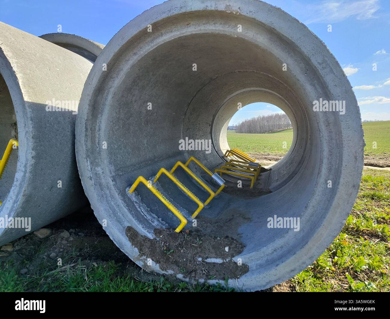 Large concrete pipes with metal barriers on grassy field under clear ...