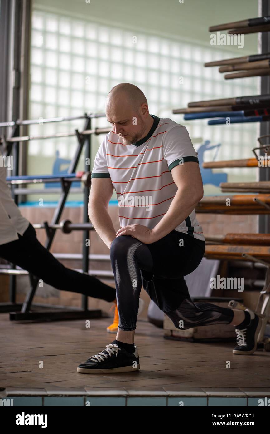 Motivated concentrated rower stretches in squat, activating muscles ...