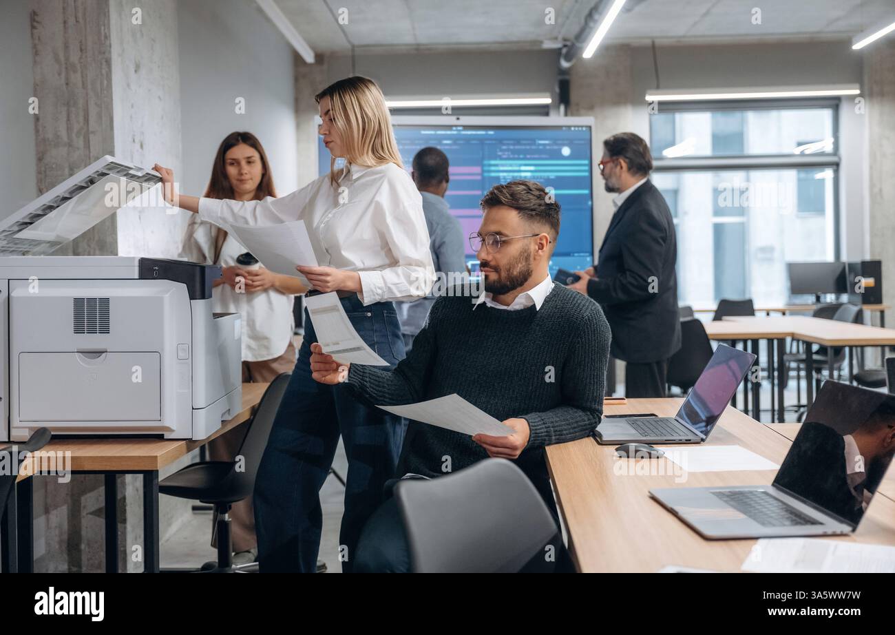 Using printer. Group of office workers are indoors together. Stock Photo