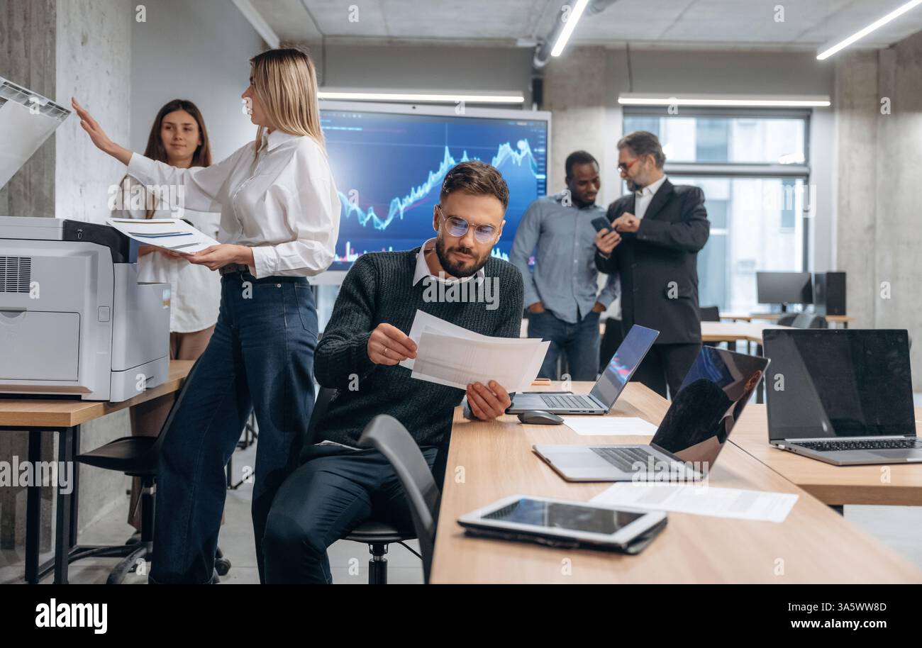 Using printer. Group of office workers are indoors together. Stock Photo