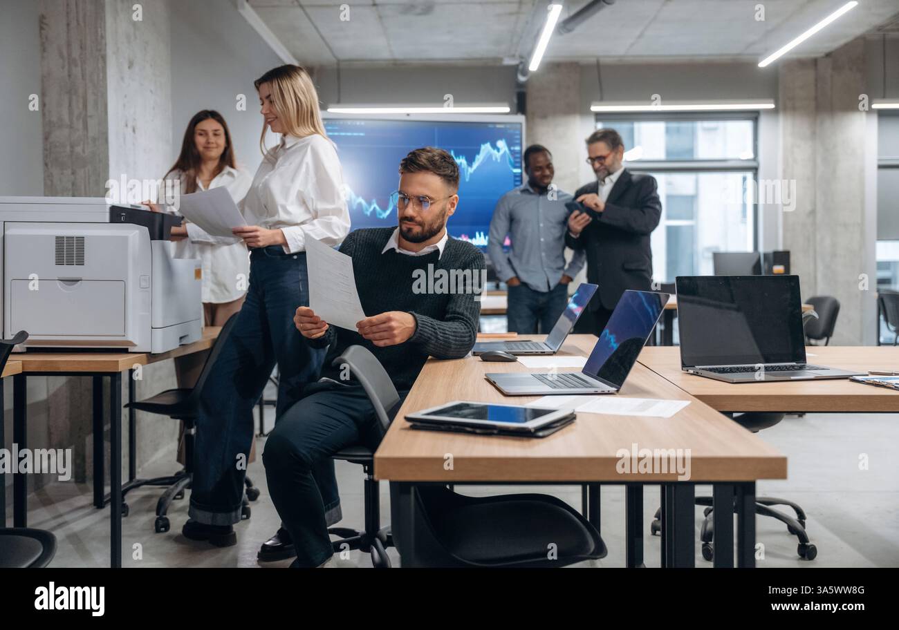 Using printer. Group of office workers are indoors together. Stock Photo