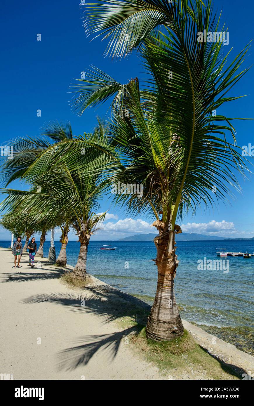 Tourists walk near the beach at Small La Laguna in Puerto Galera ...