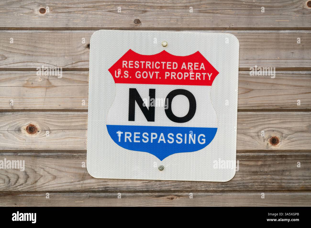 UNITED STATES — A standard government warning sign marking a restricted area on U.S. government property. The red and white sign displays the clear message 'RESTRICTED AREA U.S. GOVT. PROPERTY NO TRESPASSING' in bold lettering, serving as an official notification that unauthorized entry is prohibited. Such signs are commonly posted at the boundaries of federal facilities, military installations, and other government-controlled areas to deter unauthorized access. Federal trespassing violations can carry significant legal penalties, including fines and potential imprisonment depending on the nat Stock Photo